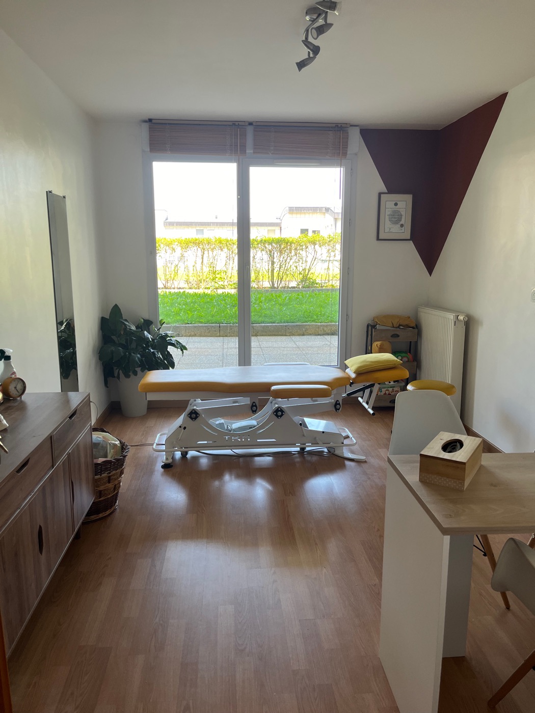 Salle de soins lumineuse avec table de pratique, ouverte sur le jardin